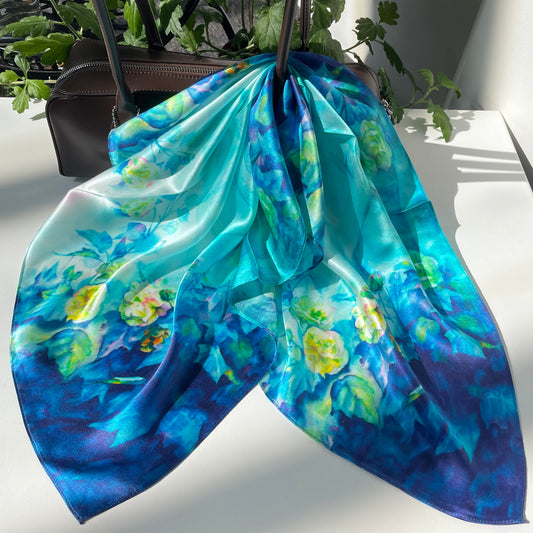 The Blue Rose scarf draped over a handbag, showing pale flowers and blue-green foliage