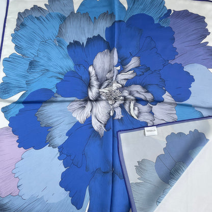 The Blue Flowers scarf with a corner folded back, revealing the reverse print and fabric label