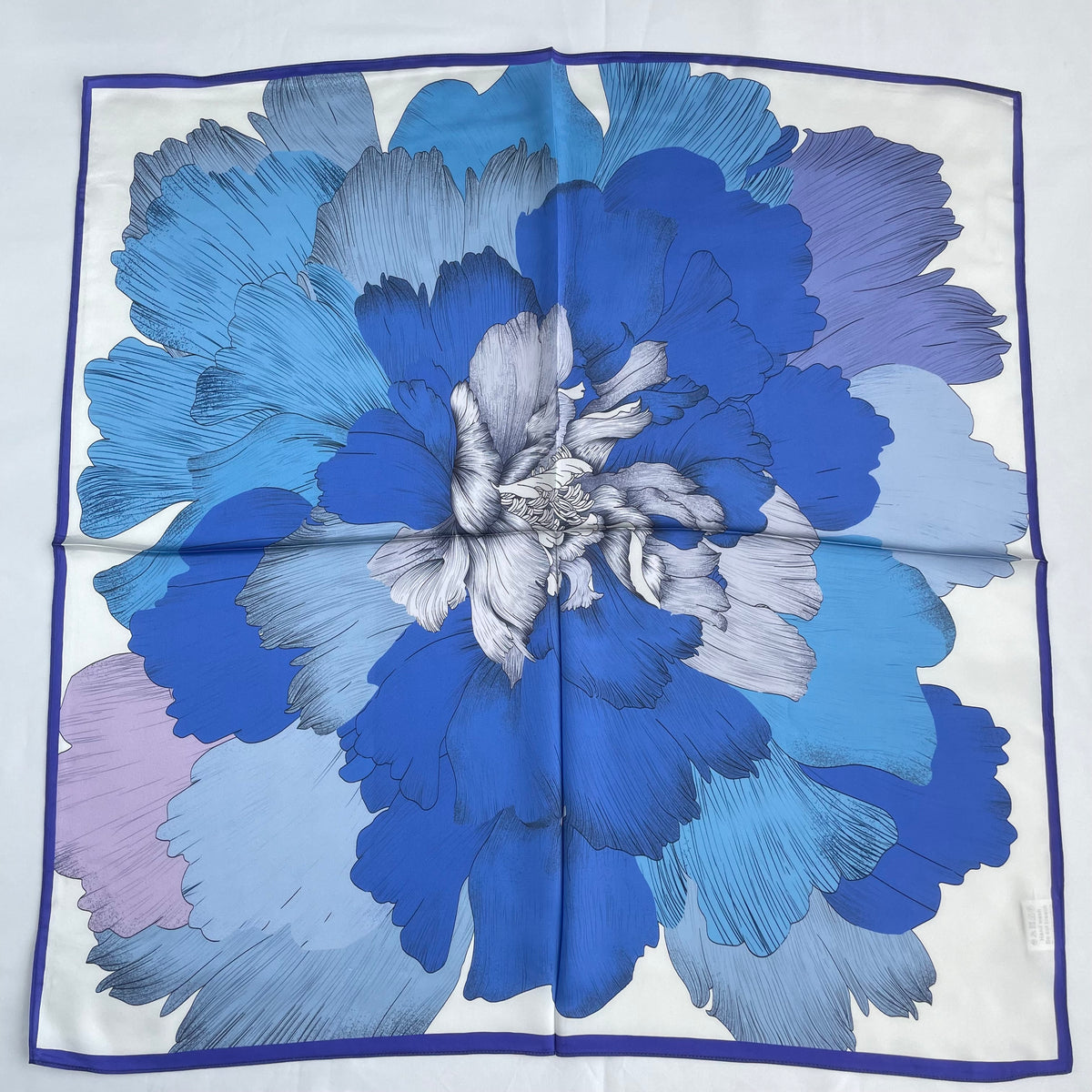 The Blue Flowers scarf laid flat, showing a large blue flower inside a narrow blue border