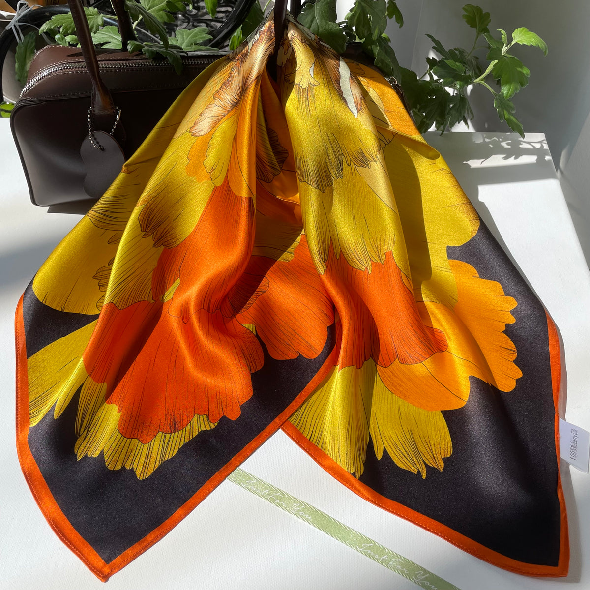 The Golden Flowers scarf draped over a handbag, showing large yellow and orange petals