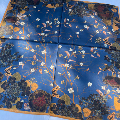 The Garden scarf laid flat, showing white blossoms, dark flowers and butterflies on blue