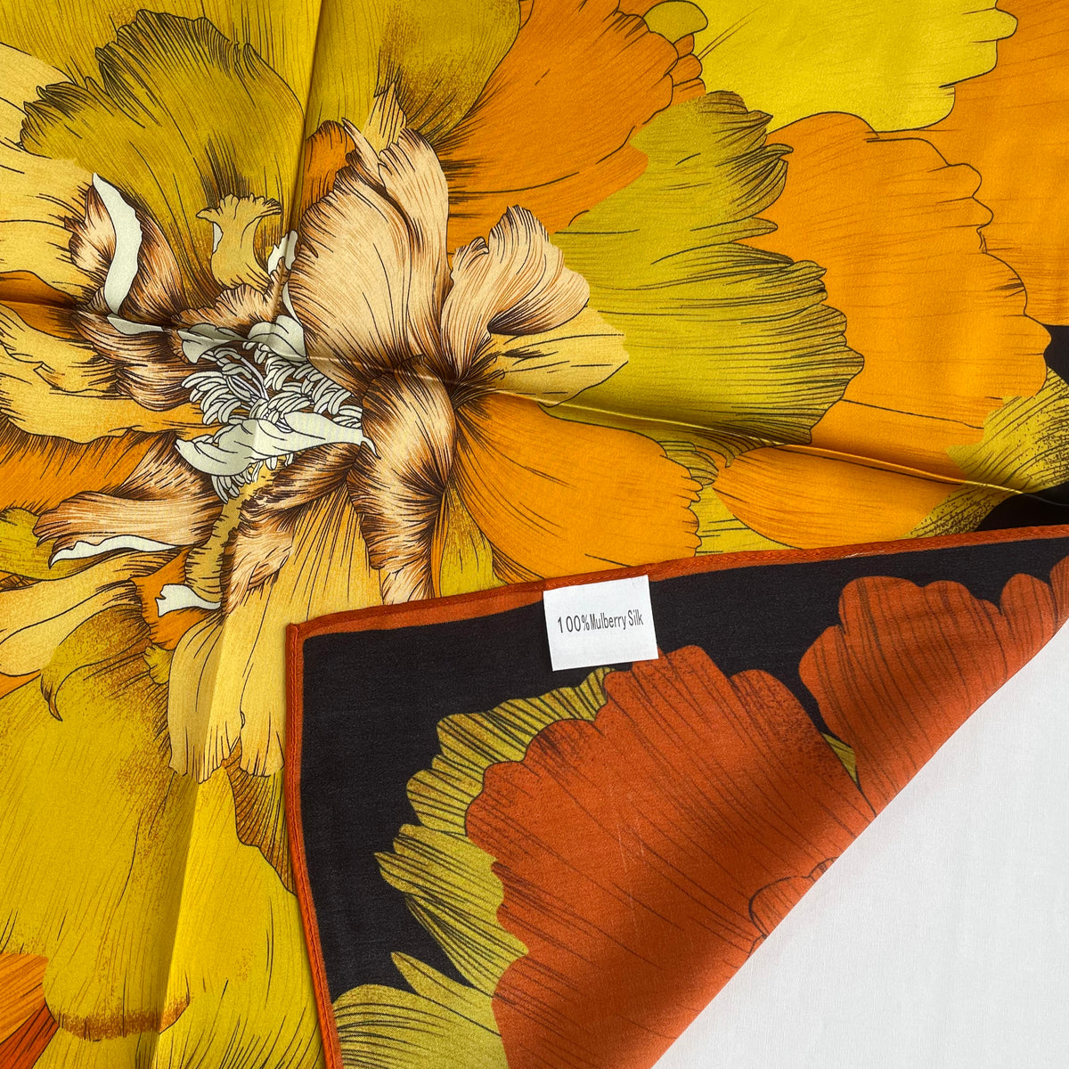 Close-up of The Golden Flowers scarf's orange edge, yellow petals and mulberry silk label