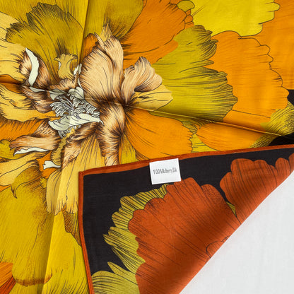 Close-up of The Golden Flowers scarf's orange edge, yellow petals and mulberry silk label
