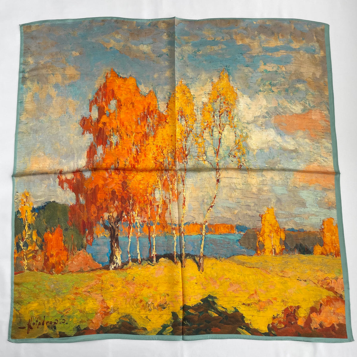 The Autumn Painting scarf laid flat, showing orange and yellow trees beside blue water
